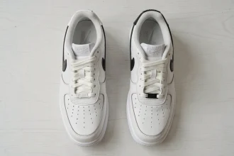 Comparaison entre une vraie Nike Air Force 1 authentique et une contrefaçon posées côte à côte sur une table blanche, vue de dessus