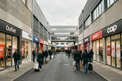 Vue d'ensemble d'une rue commerçante de magasins d'usine dans le Rhône avec des enseignes de marques et des acheteurs