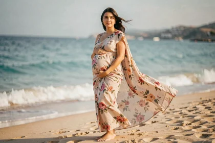 Femme enceinte portant un paréo robe fleuri sur une plage de sable fin avec mer turquoise en fond